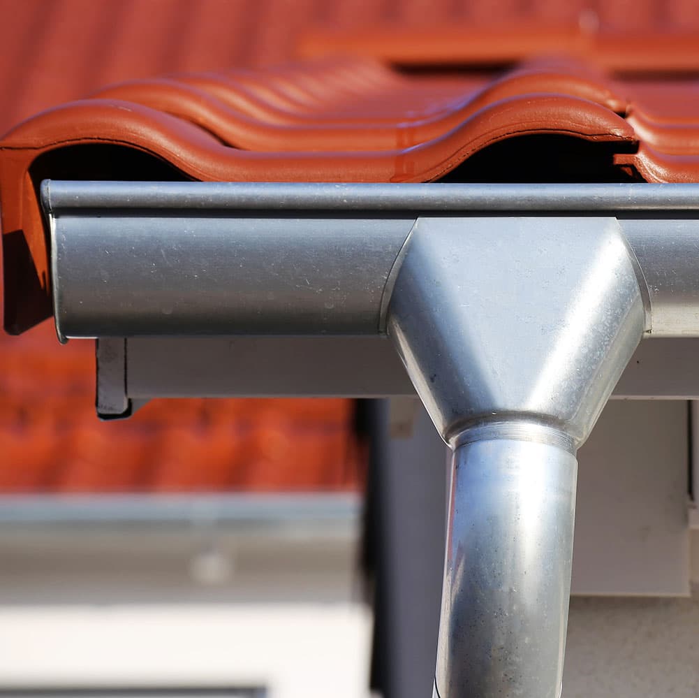 Raccord de gouttière en zinc posé par Techni Couverture sur une toiture en tuiles